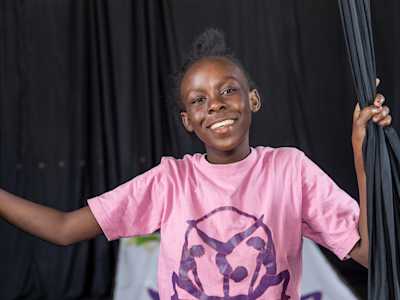 Precious, participant of 'Rise up Girls!', smiles wearing a pink t-shirt featuring the organisation's logo.