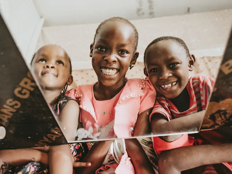 Three children smiling at the camera.