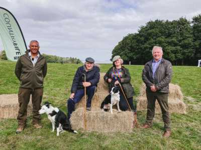 Countryfile cast sitting on a bale of hay with their dog.