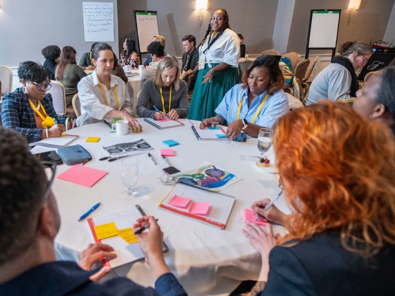 Several participants sitting around a table at a conference taking notes