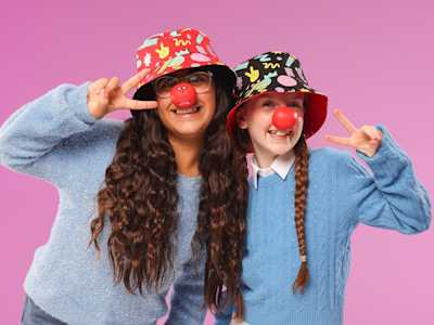 Two girls wearing hats and red noses