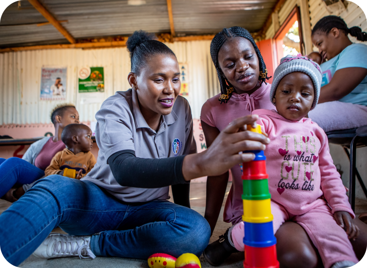 A children's care worker plays with a child and their parent.