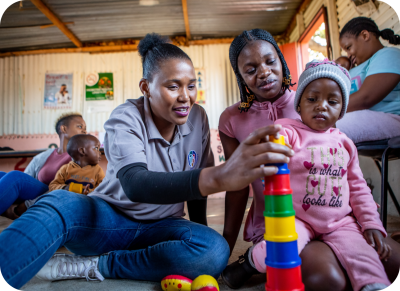 A children's care worker plays with a child and their parent. 