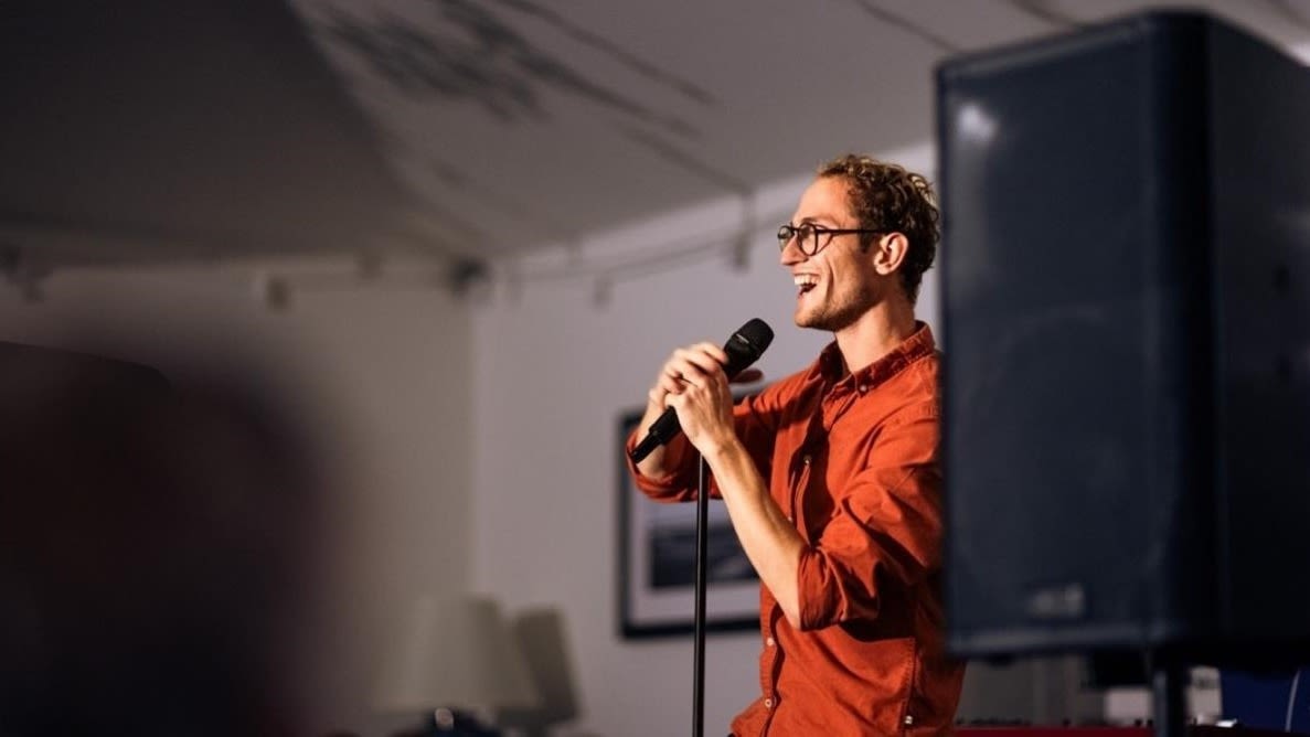 A man performs comedy onstage at the Alverbank.