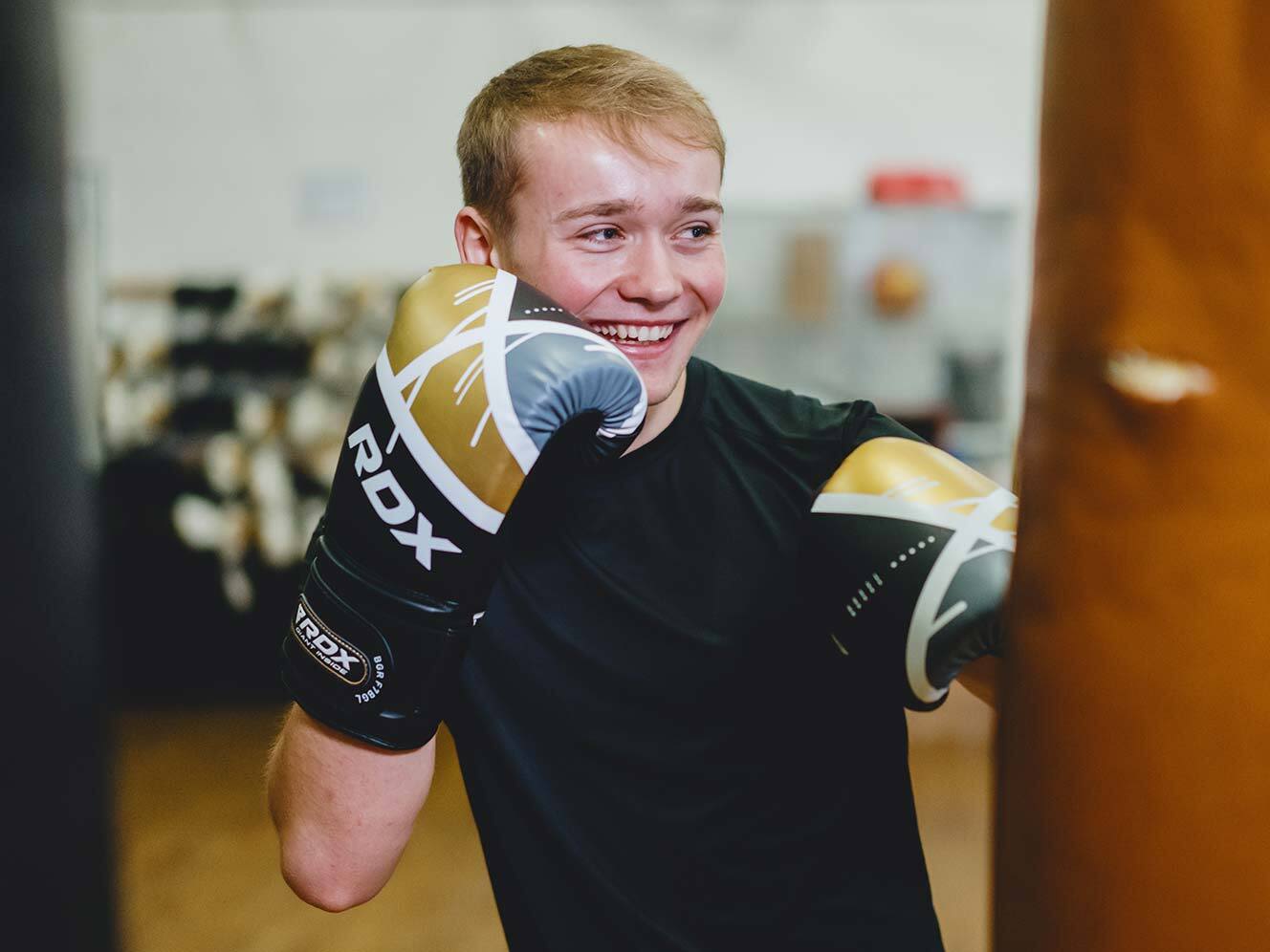 Billy smiling as he punches a punching bag.