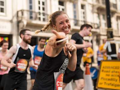 Female participant of a charity run smiling and pointing at the camera