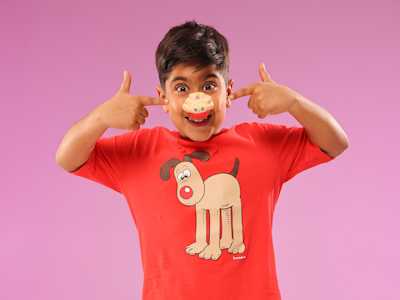 A child wearing a red t-shirt smiling and posing for the camera