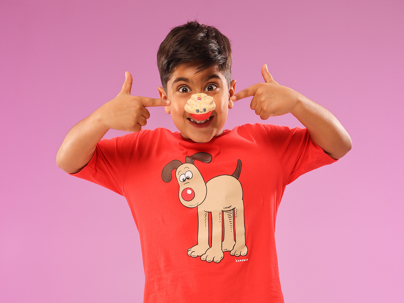 A child wearing a red t-shirt smiling and posing for the camera