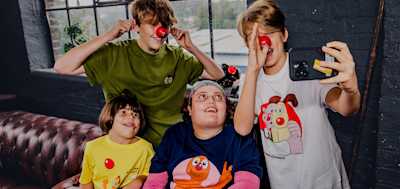 A group of four children enjoy themselves and goof around while wearing Comic Relief merchandise for Red Nose Day 2024.