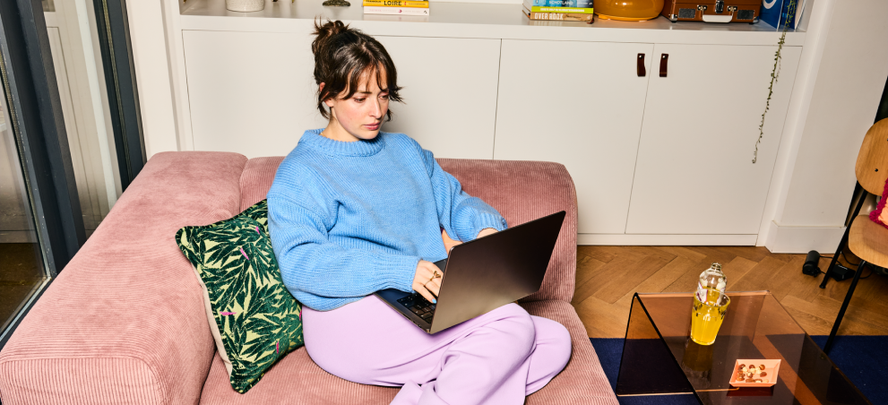Vrouw zit op de bank en werkt op haar laptop