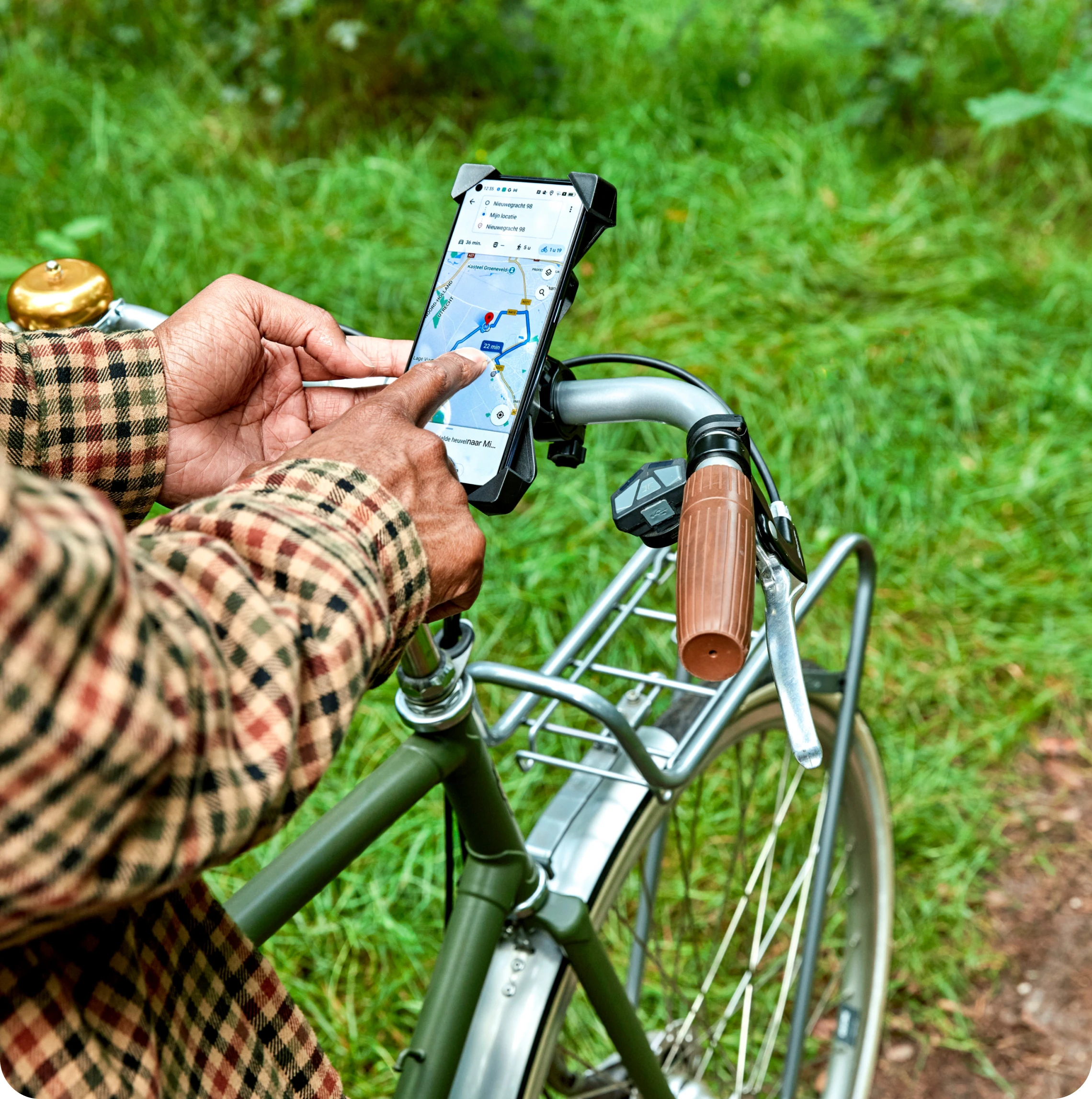 Persoon met een fiets zoekt een route in een navigatie-app op de telefoon.