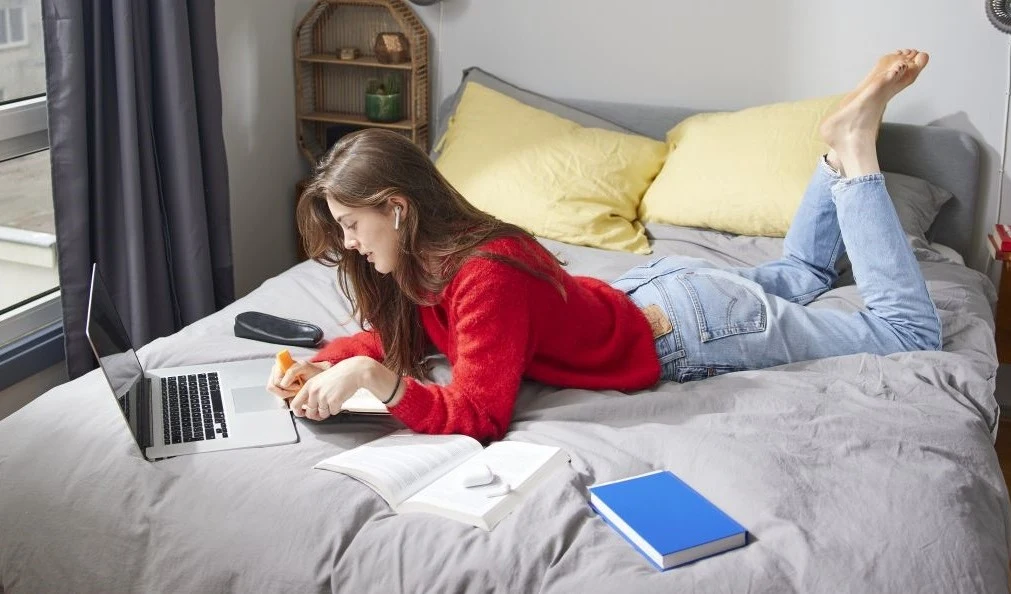 Vrouw ligt op bed met laptop 