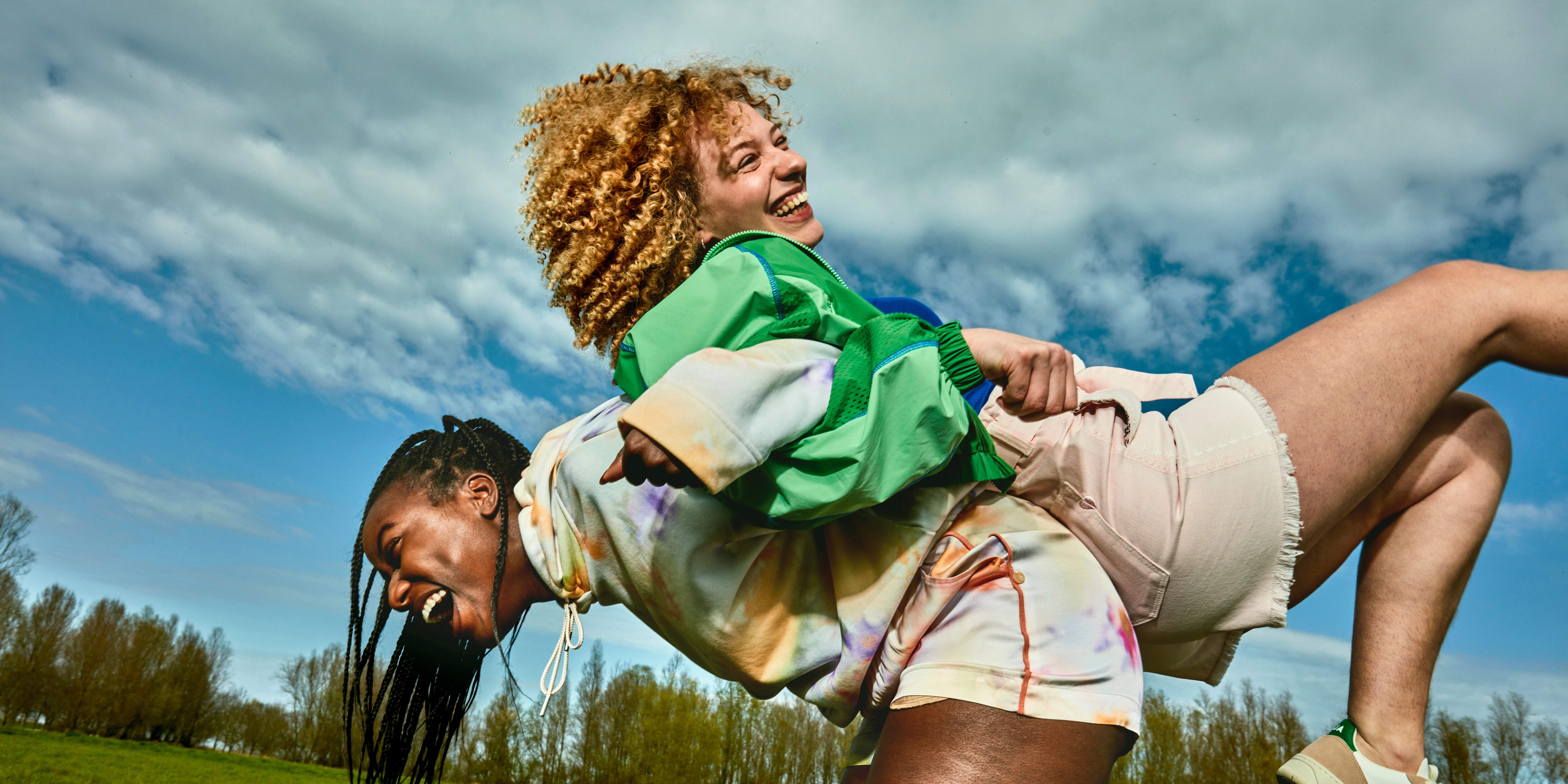 twee lachende en spelende vrouwen in een grasveld