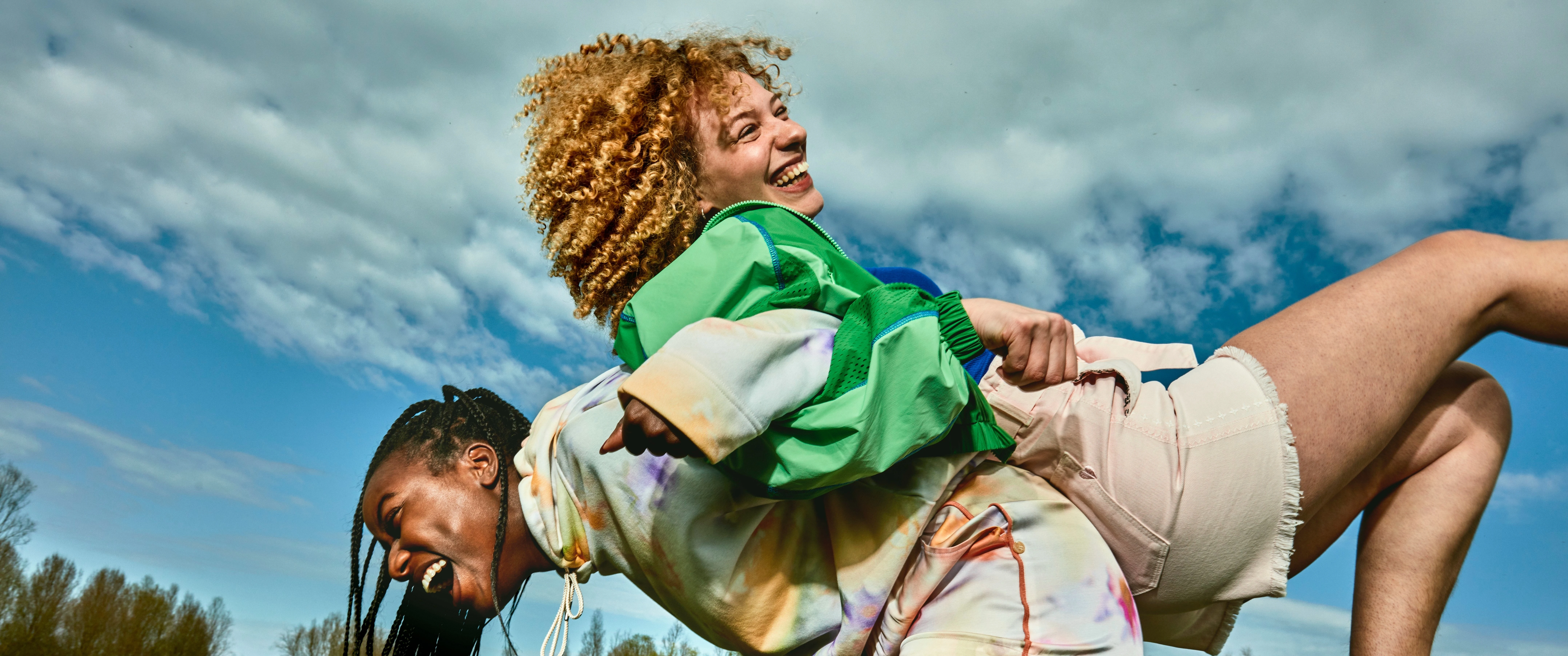 twee lachende en spelende vrouwen in een grasveld