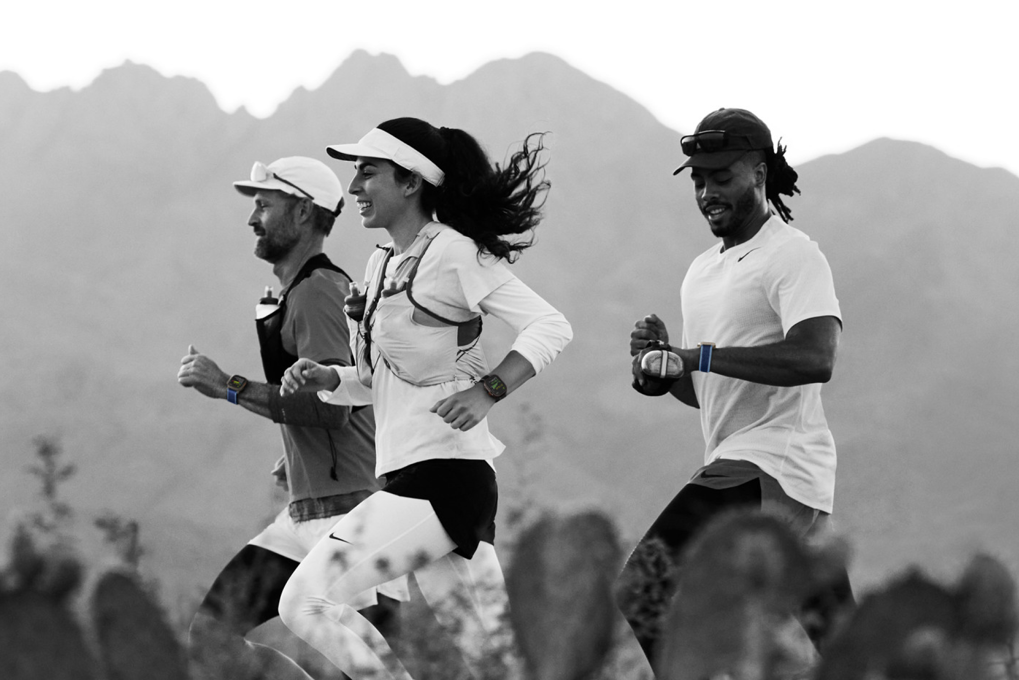 Drie mensen lopen hard en kijken op hun Apple Watch
