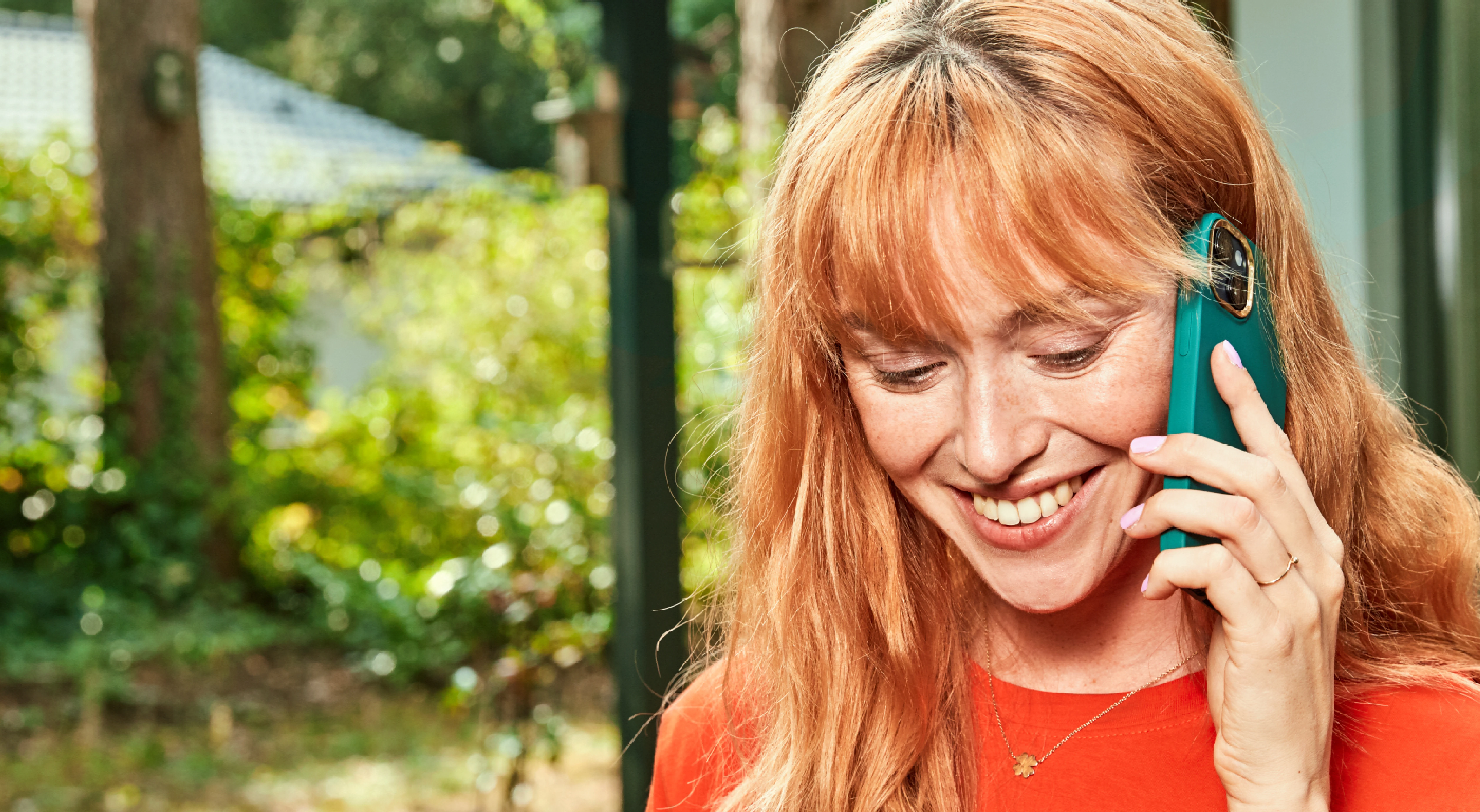 Er staat een vrouw buiten glimlachend te bellen