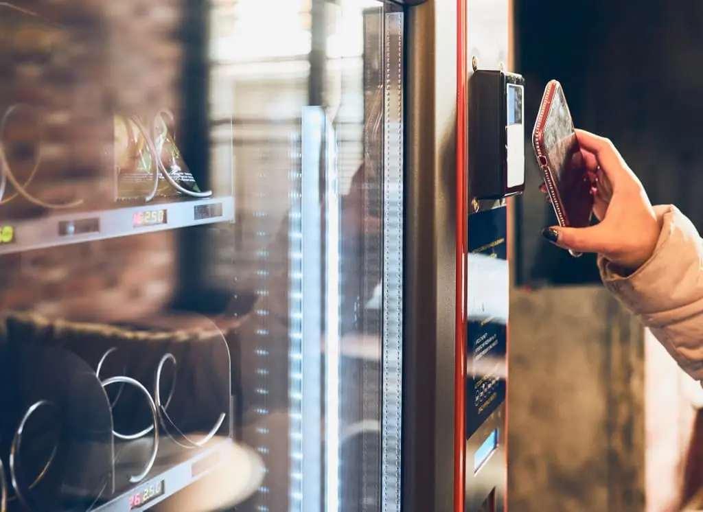 Iemand houdt de telefoon bij een snackautomaat om te betalen