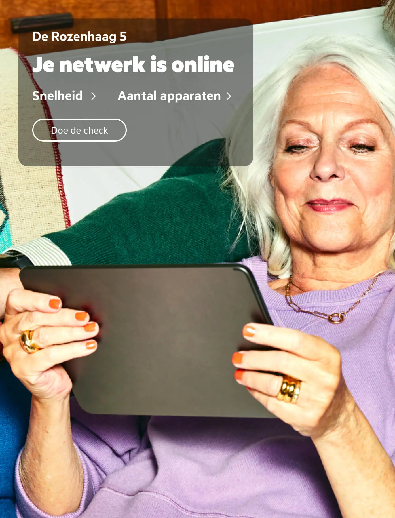 Op de achtergrond een oudere dame die op een tablet kijkt. Daaroverheen een app-melding met de tekst: De Rozenhaag 5. Je netwerk is online. Snelheid > Doe de Check. Apparaten > 10.