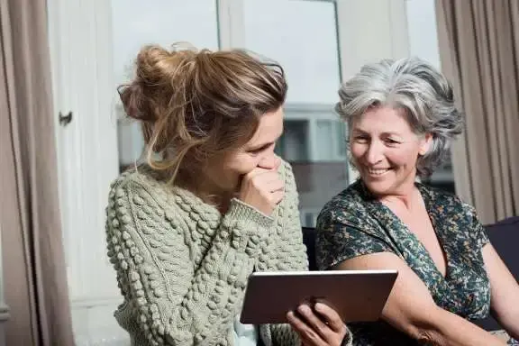 Moeder en dochter zitten naast elkaar en kijken op een tablet