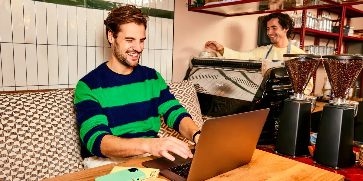 Man zit in restaurant en werkt aan tafel op laptop 