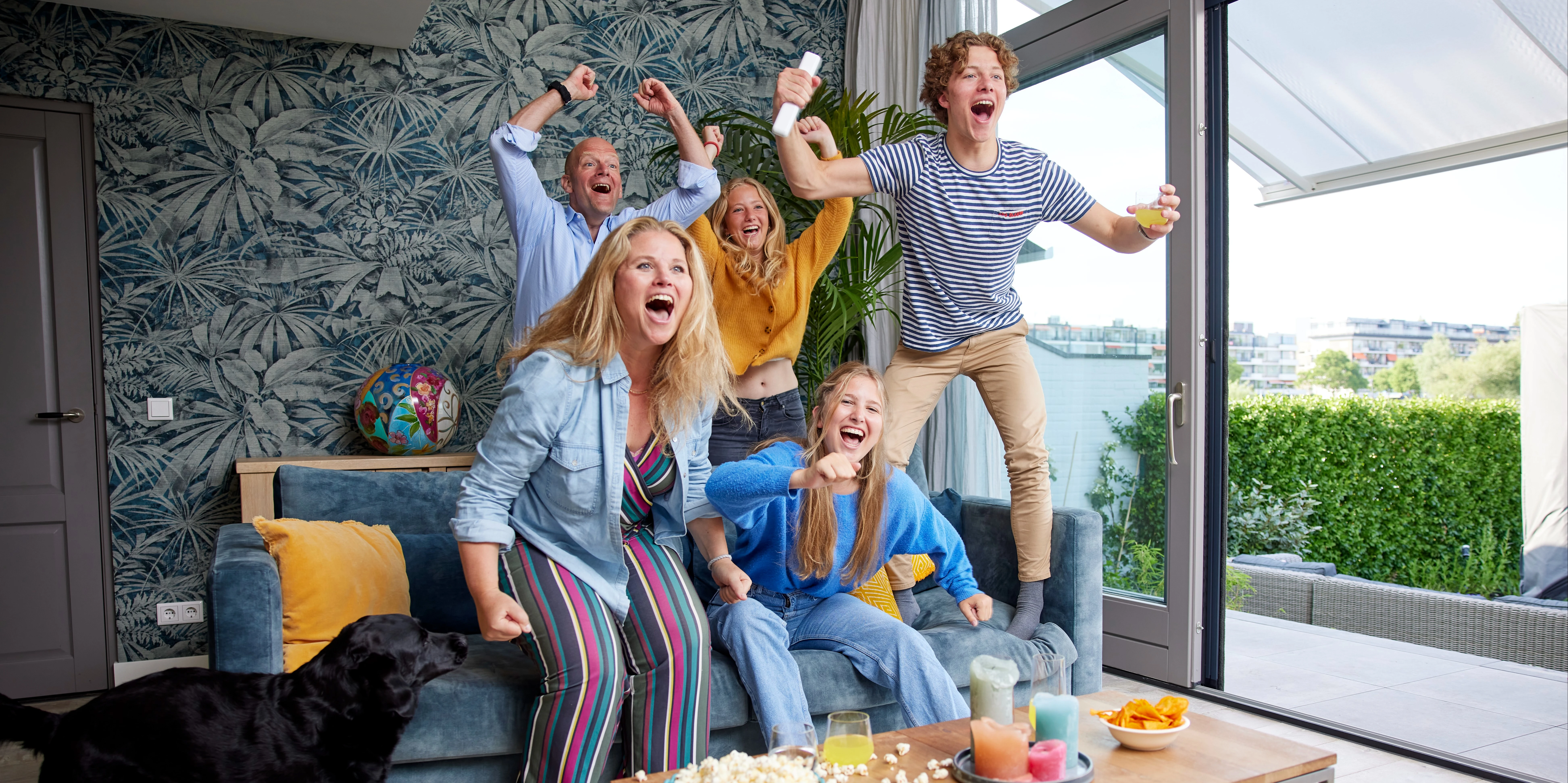 Gezin met tieners staat juichend op van de bank voor de tv