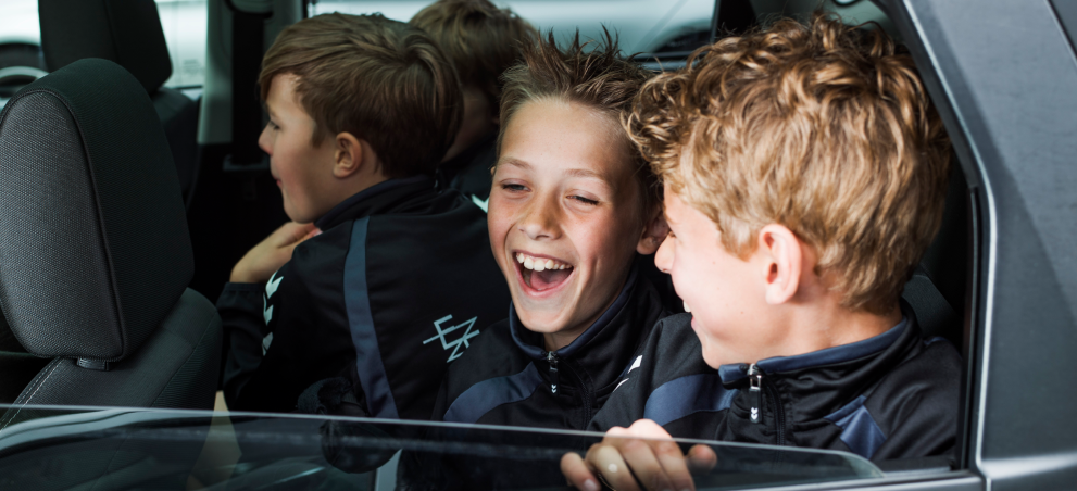 3 jongens zitten lachend op de achterbank van een auto