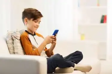 Jongetje in een stoel kijkt op zijn mobiele telefoon