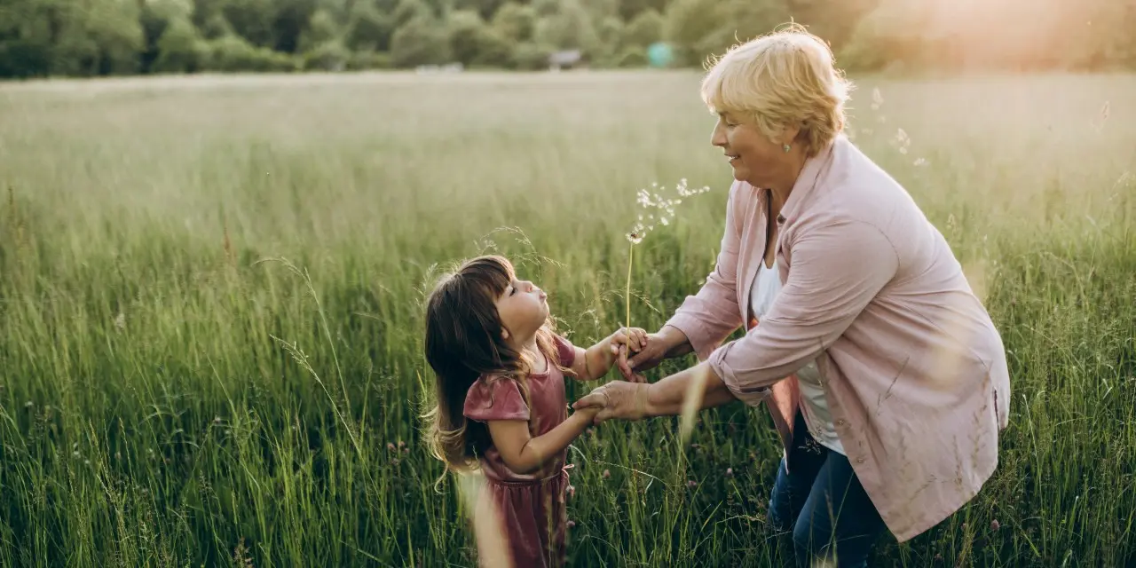 Oudere vrouw (oma) met (klein)kind in een grasveld