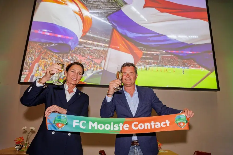 Twee personen tonen de sjaal van FC Mooiste Contact en heffen het glas voor een toost