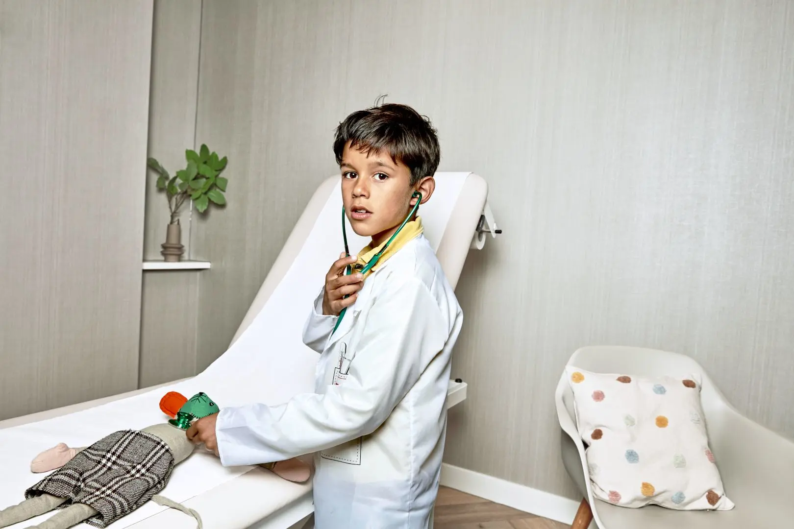 Jongen kijkt in de camera in zijn handen heeft hij medisch speelgoed