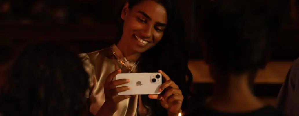 Meisje die aan het filmen is met een iPhone 14 Plus. De achtergrond is donker