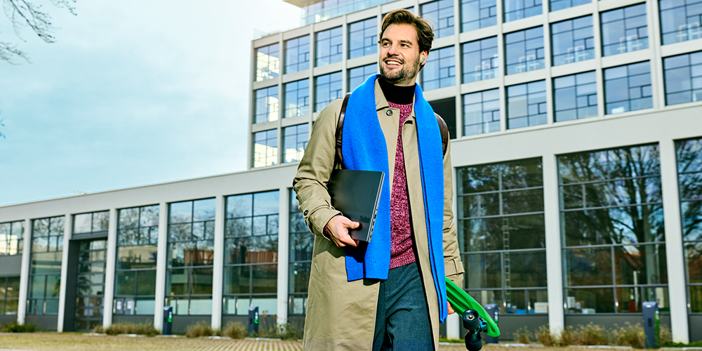 Man komt uit werk met laptop en skateboard