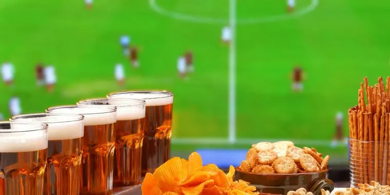Bier en snacks met een voetbalwedstrijd op de achtergrond