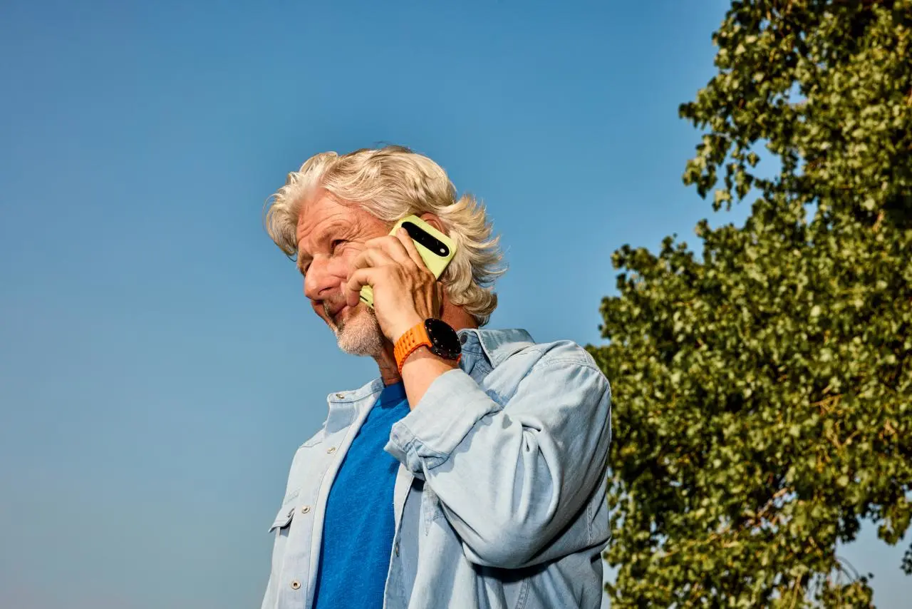 Een man die buiten staat houdt zijn smartphone tegen zijn oor