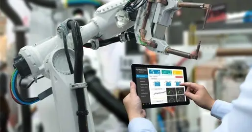 Medewerker houdt een tablet vast in de buurt van een robotmachine