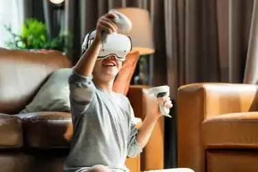 Jongen met VR-bril op en joystick in zijn hand is een spe laan het spelen