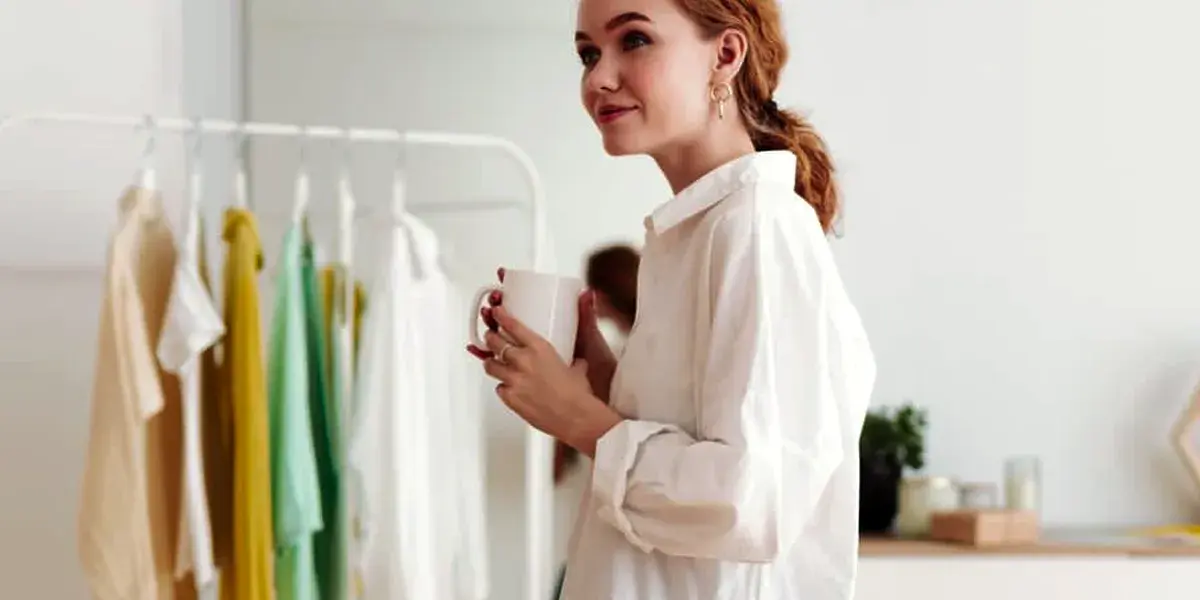 Vrouw staat met mobiel in hand voor kledingrek