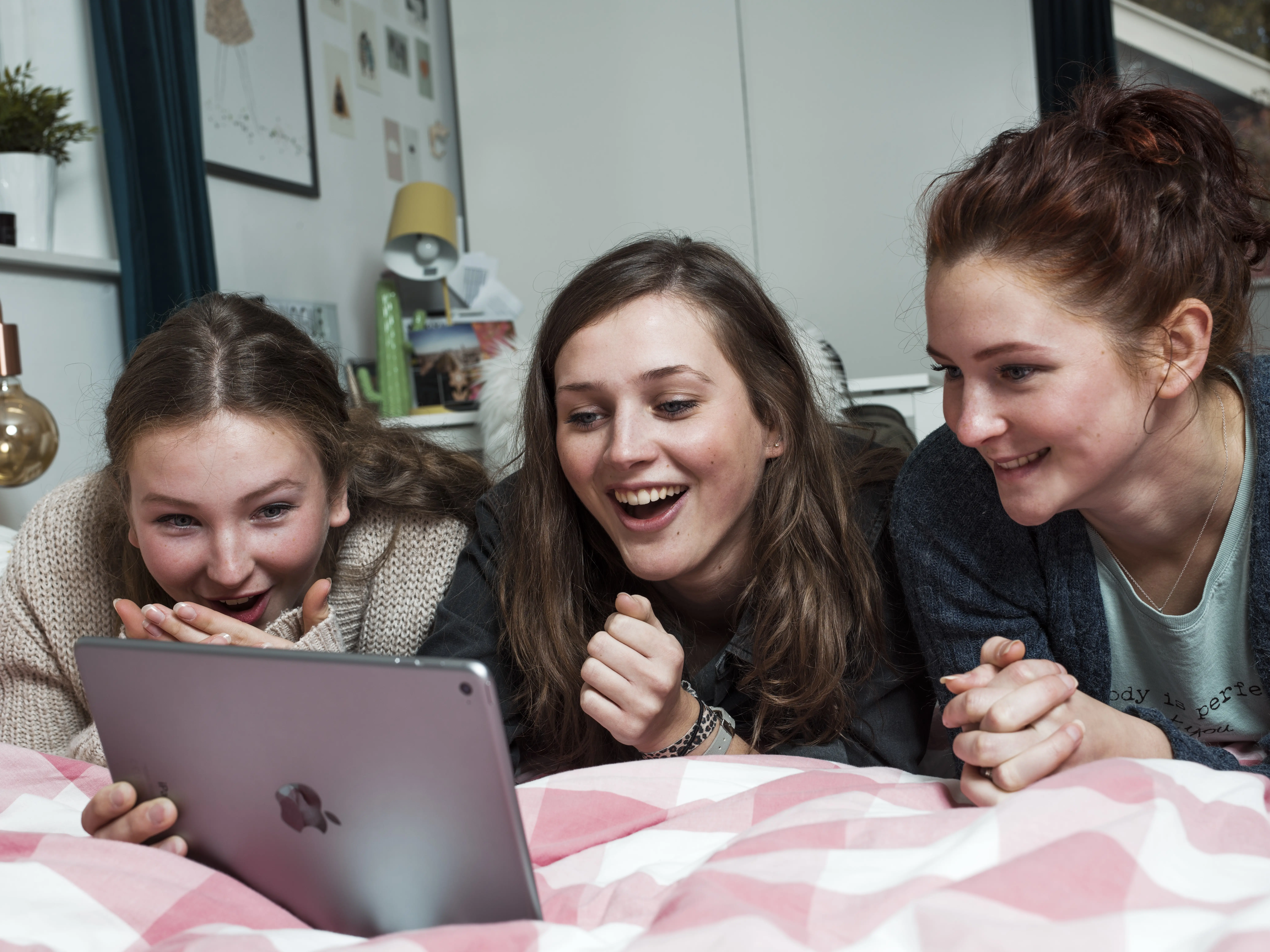 drie meiden op bed die kijken naar een ipad