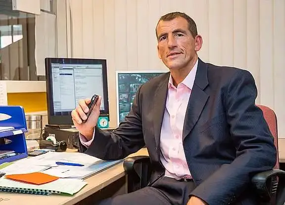 Man zit achter een bureau kijkt naar de camera
