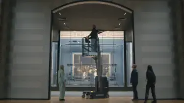 Mensen lopen door het rijksmuseum, en één iemand staat op een hoogwerker