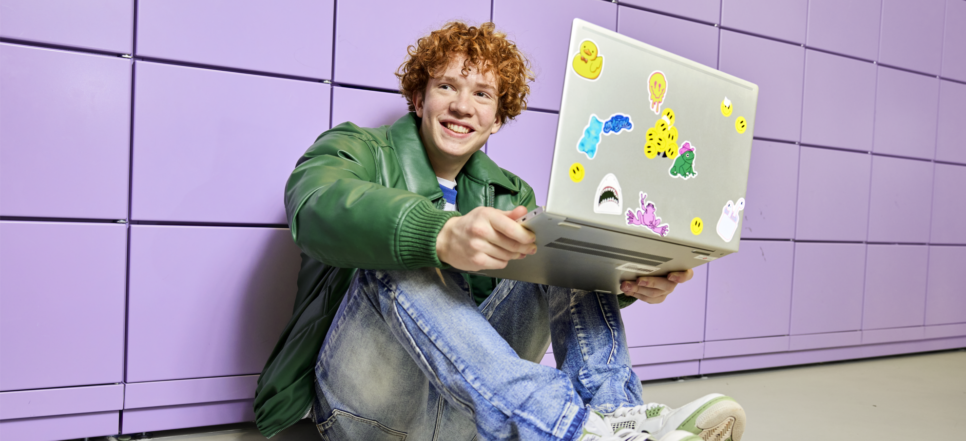 Jongen met laptop voor paarse wand