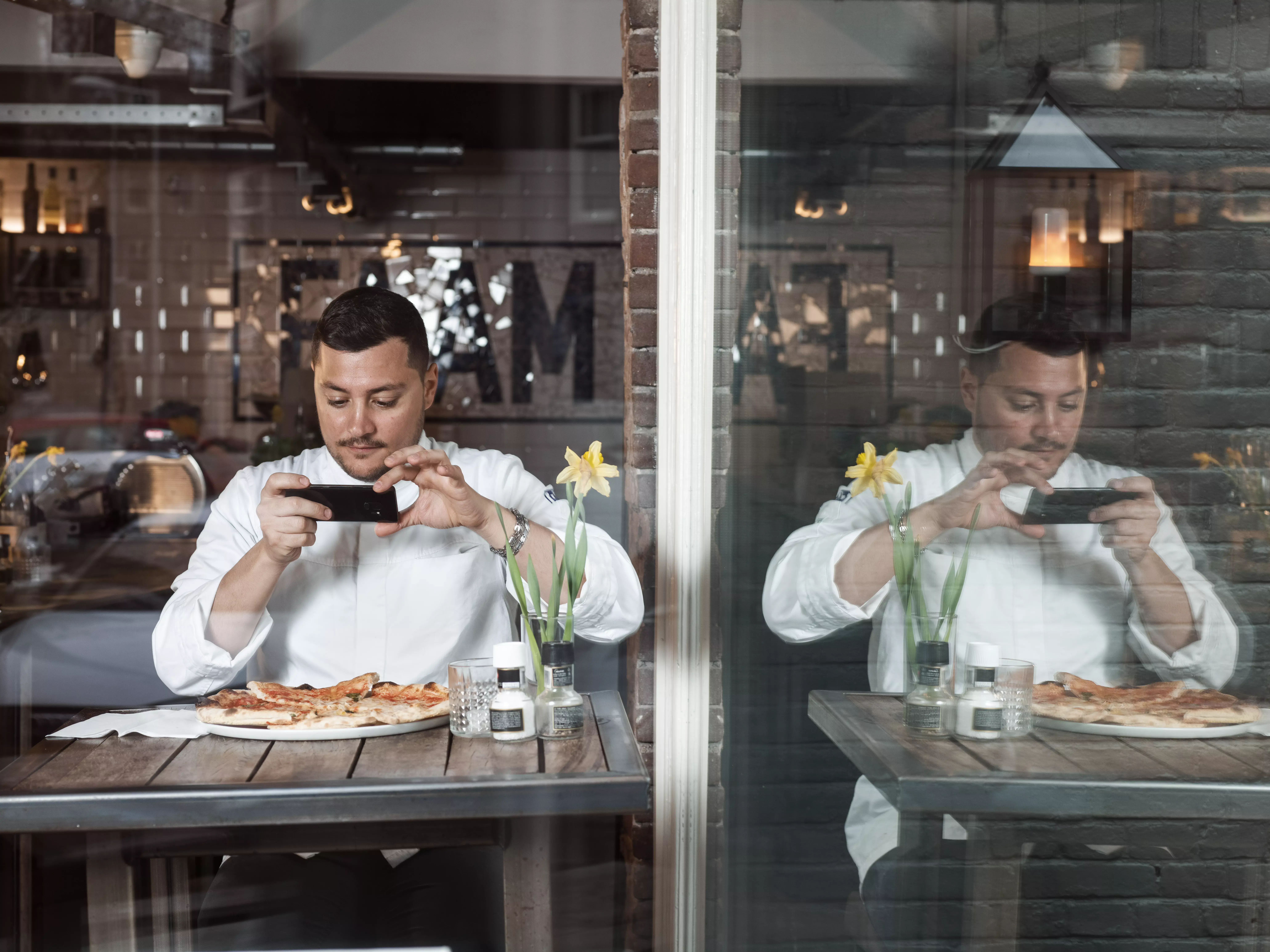 Italiaanse kok fotografeert pizza in een restaurant