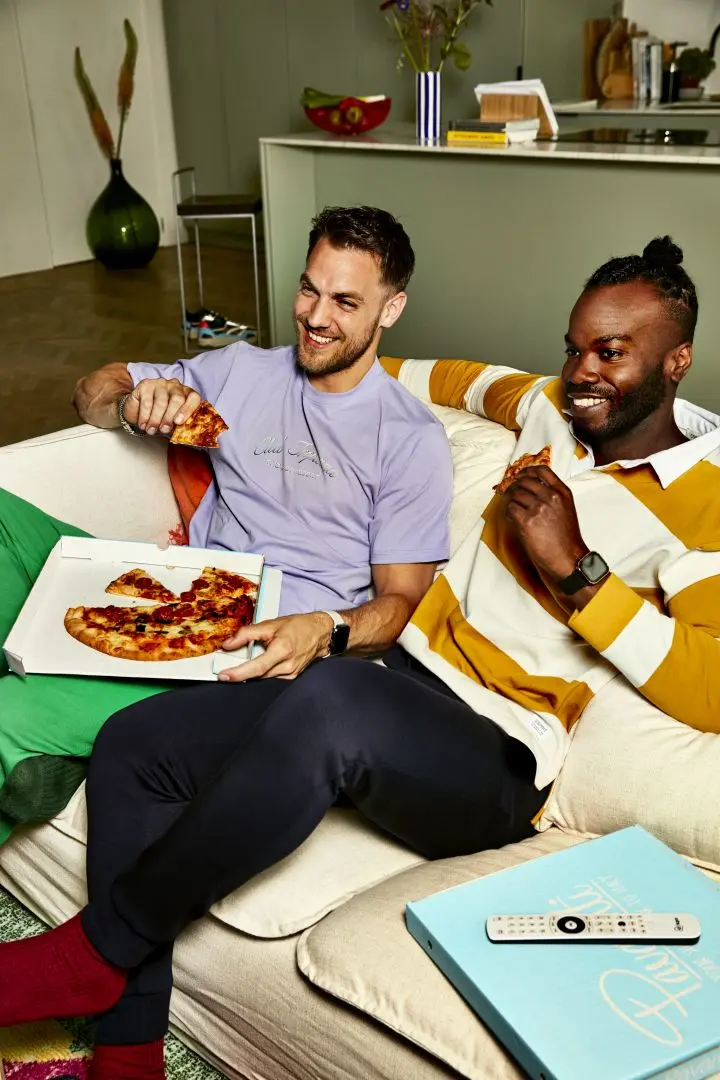 2 mannen eten pizza op de bank