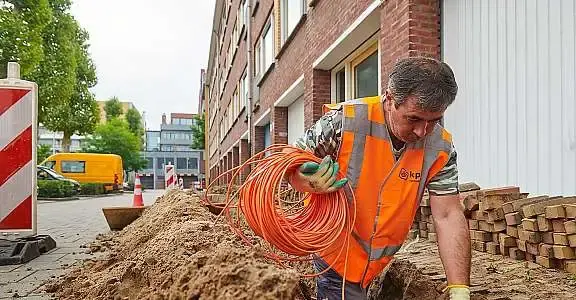Monteur bezig met het leggen van glasvezelkabels in de grond