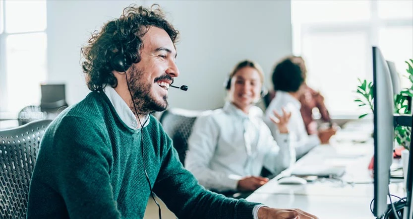 Mannelijke callcenter medewerker lacht naar computerscherm