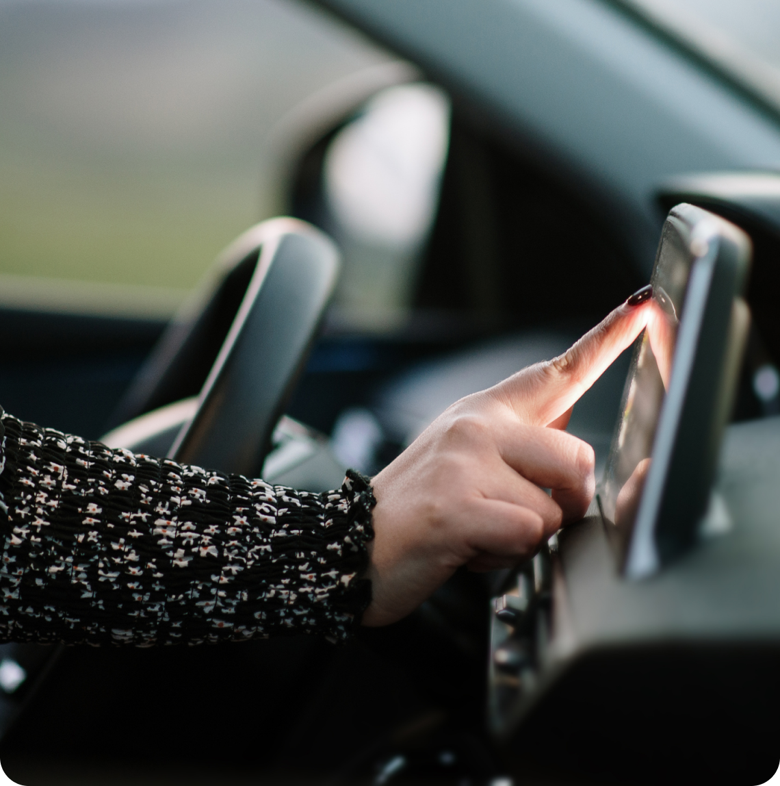 Bestuurder zit in een auto en raakt het scherm van de navigatie aan