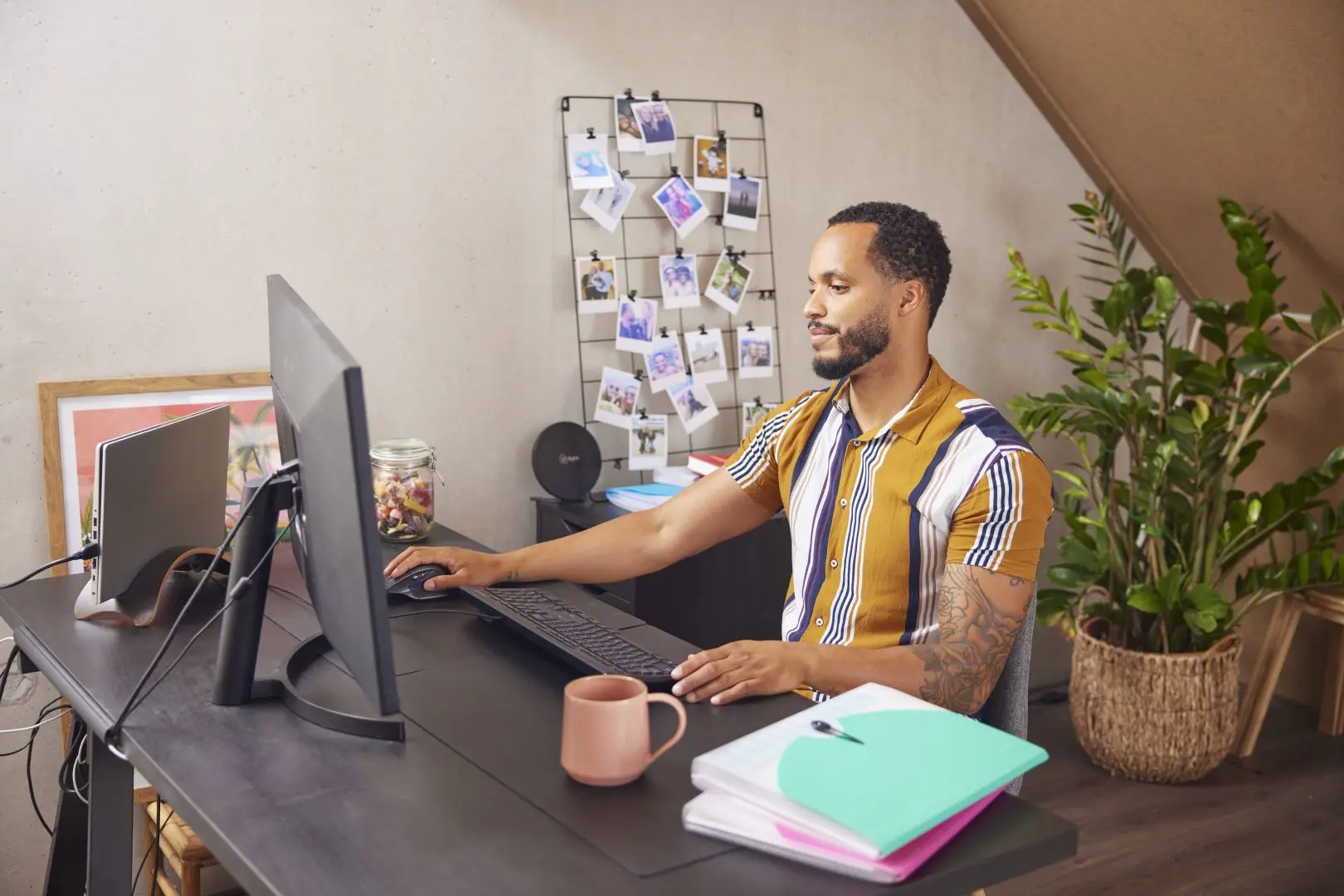 Man achter een computer in een thuiskantoor met mappen op zijn bureau
