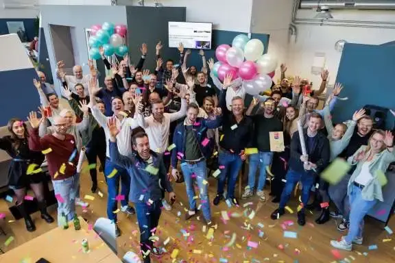 Groep mensne vieren iets, met ballonnen en confettie