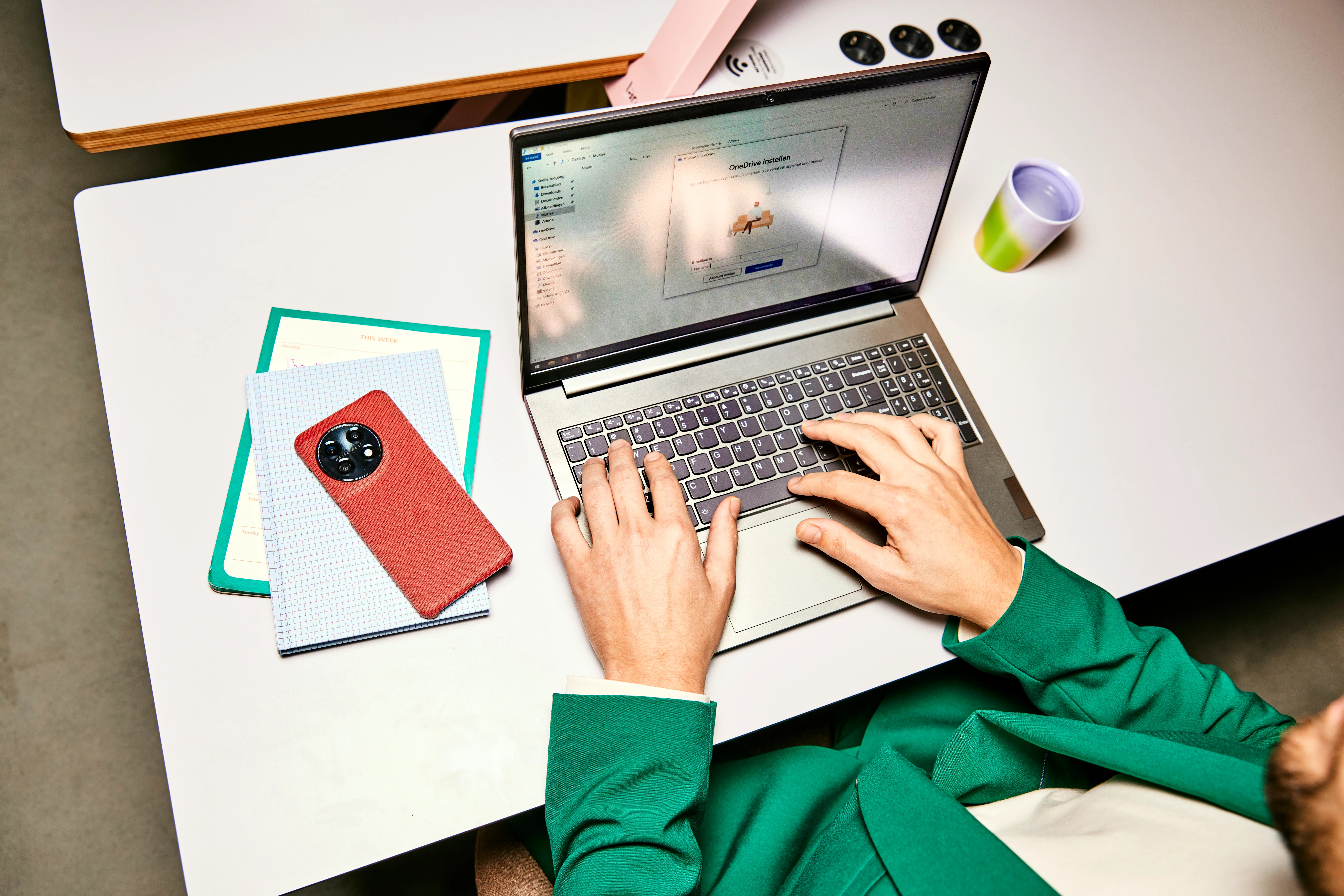 Een man werkt op zijn laptop aan een bureau. 