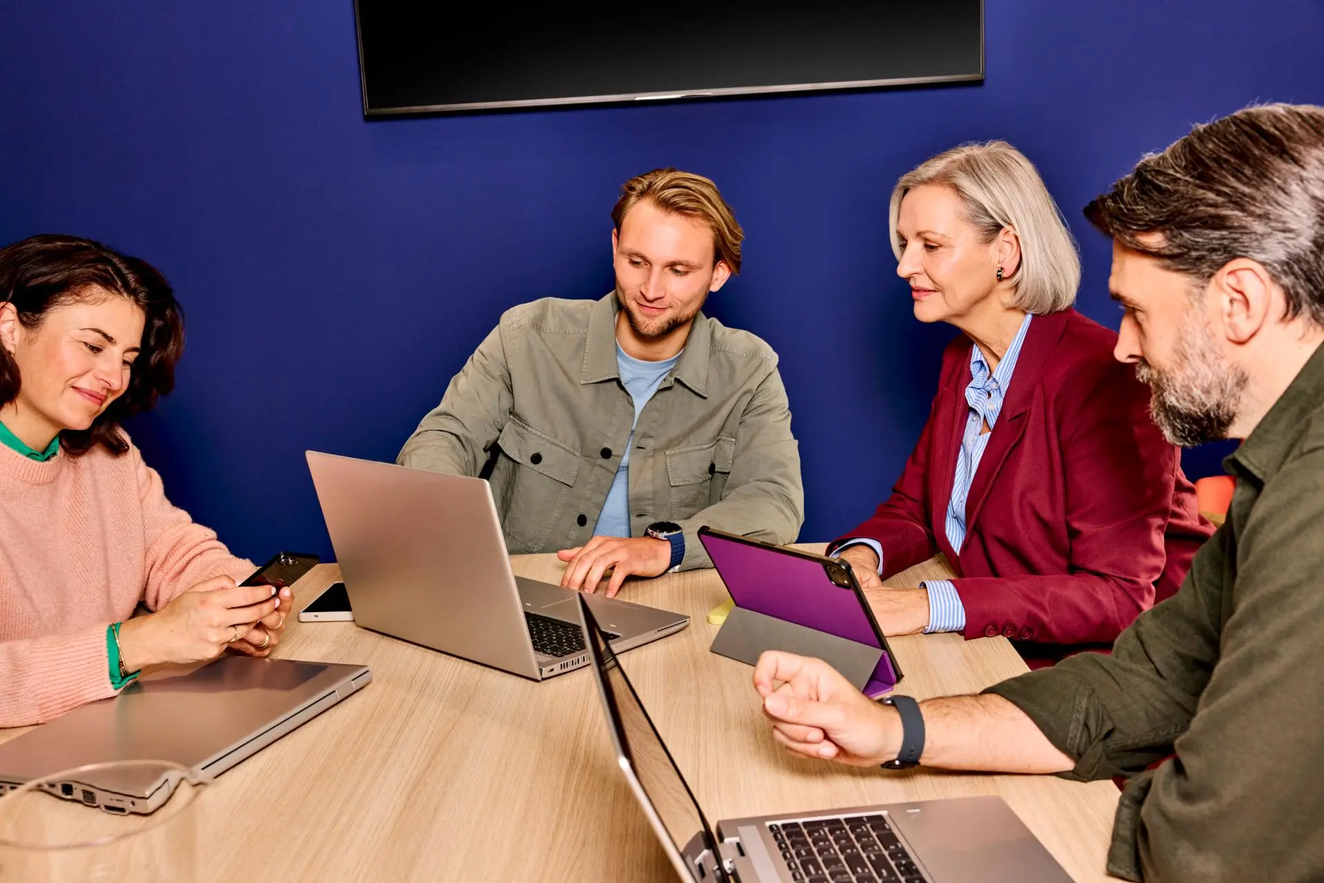 Collega's zitten in vergaderzaal en kijken naar laptop